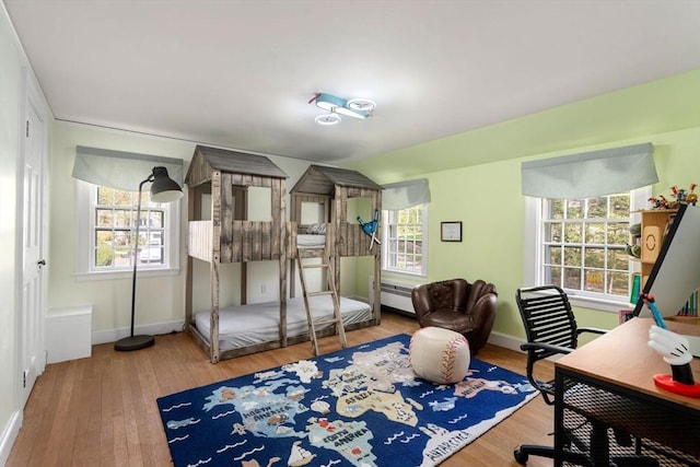 bedroom with baseboards, wood finished floors, and multiple windows