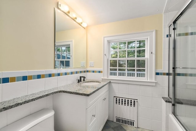 full bathroom featuring vanity, toilet, radiator, a wainscoted wall, and tile walls