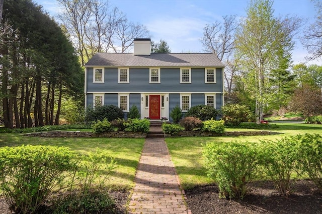 colonial house with a front yard and a chimney