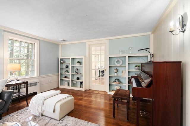 living area with visible vents, wood finished floors, and radiator