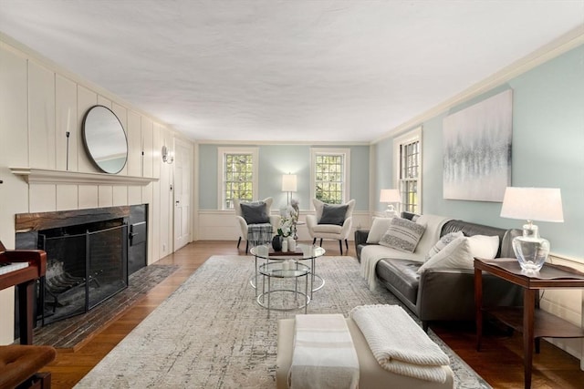 living area with ornamental molding, wood finished floors, and a tile fireplace