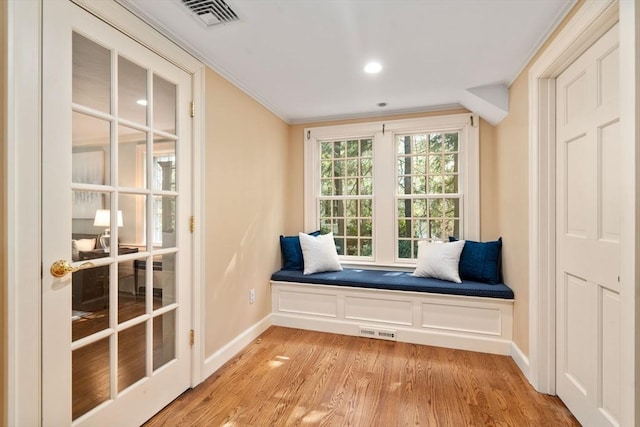 sitting room featuring visible vents, baseboards, crown molding, and light wood-style floors