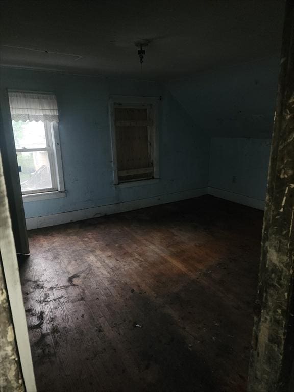 additional living space with wood-type flooring, vaulted ceiling, and baseboards
