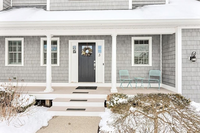 snow covered property entrance featuring covered porch