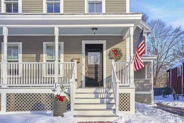 snow covered property entrance with a porch