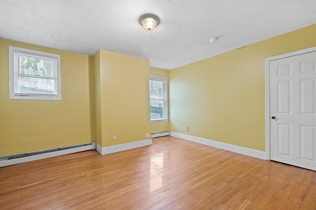 36 Brookford St, Boston, MA 02125 - empty room featuring a baseboard heating unit, light wood-type flooring, and baseboards