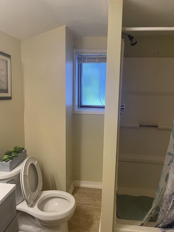 full bath with a stall shower, toilet, vanity, and baseboards