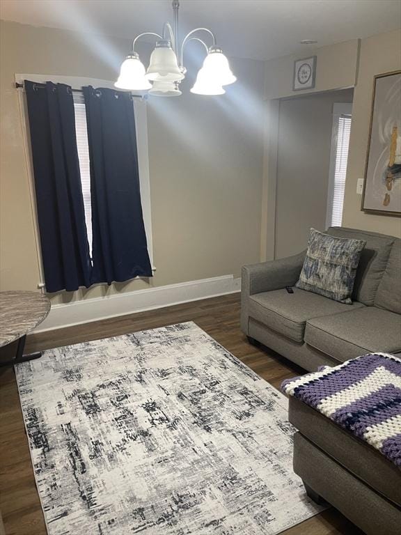 living area with wood finished floors, baseboards, and a chandelier