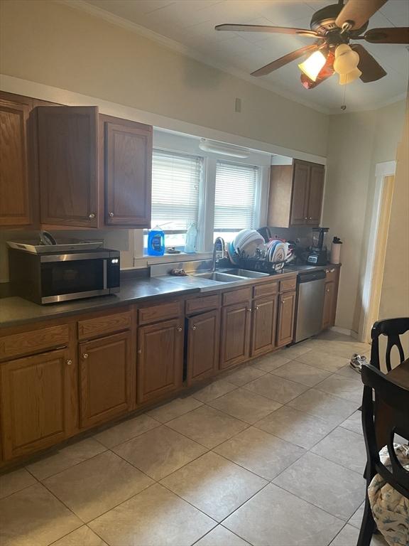 kitchen with ceiling fan, ornamental molding, light tile patterned floors, appliances with stainless steel finishes, and a sink