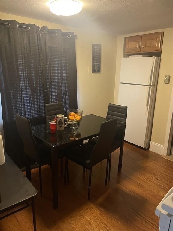 dining space featuring wood finished floors, baseboards, and a textured ceiling