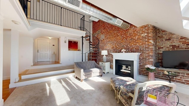 52 Sanborn St Unit 408, Reading, MA 01867 - living area with a glass covered fireplace, brick wall, baseboards, a high ceiling, and visible vents