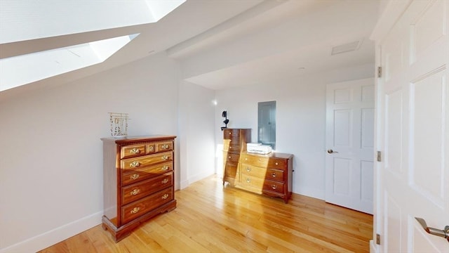 52 Sanborn St Unit 408, Reading, MA 01867 - bedroom featuring baseboards, vaulted ceiling with skylight, and light wood-style flooring