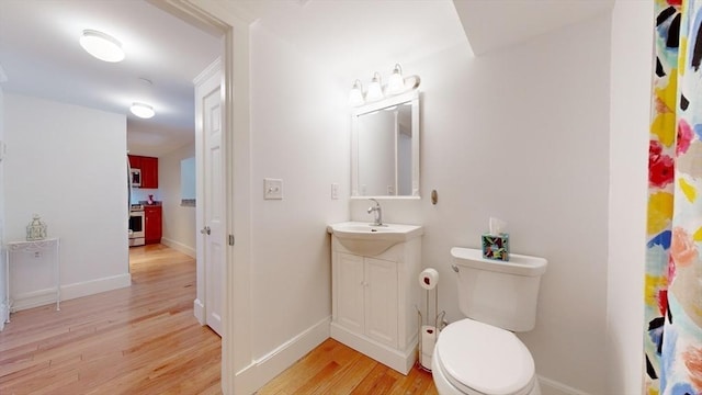 52 Sanborn St Unit 408, Reading, MA 01867 - bathroom featuring baseboards, wood finished floors, toilet, and vanity