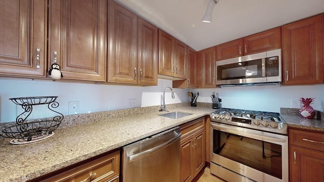 52 Sanborn St Unit 408, Reading, MA 01867 - kitchen featuring brown cabinetry, light stone counters, a sink, and appliances with stainless steel finishes