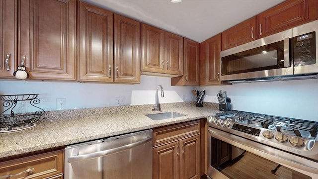 52 Sanborn St Unit 408, Reading, MA 01867 - kitchen with light stone counters, brown cabinetry, stainless steel appliances, and a sink