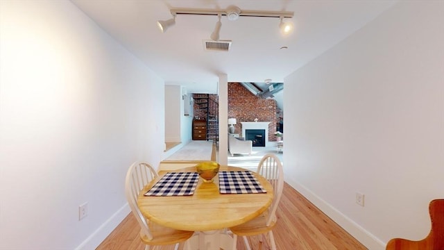 52 Sanborn St Unit 408, Reading, MA 01867 - dining space featuring light wood-type flooring, track lighting, baseboards, a brick fireplace, and visible vents
