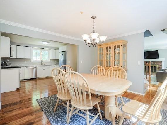 230 2nd St, Stoughton, MA 02072 - dining area with a chandelier, light wood-style flooring, ornamental molding, a fireplace, and baseboards