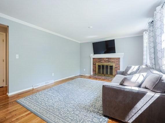 230 2nd St, Stoughton, MA 02072 - living area with crown molding, wood finished floors, baseboards, and a brick fireplace