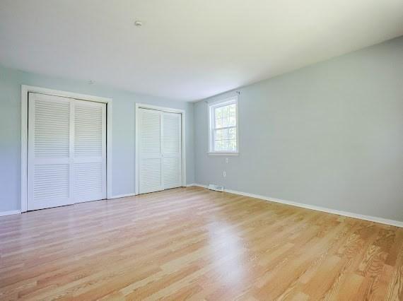 230 2nd St, Stoughton, MA 02072 - unfurnished bedroom with two closets, light wood-style floors, and baseboards