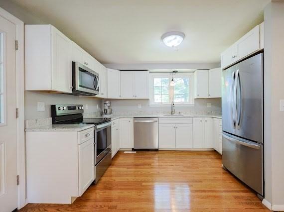 230 2nd St, Stoughton, MA 02072 - kitchen featuring stainless steel appliances, a sink, light wood-style flooring, and white cabinets