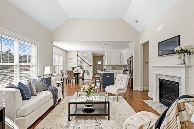 living room featuring a premium fireplace, sink, hardwood / wood-style floors, and high vaulted ceiling