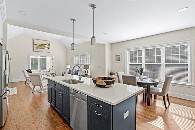 kitchen with sink, a kitchen island with sink, a healthy amount of sunlight, decorative light fixtures, and stainless steel dishwasher