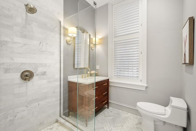 bathroom featuring a tile shower, toilet, and vanity