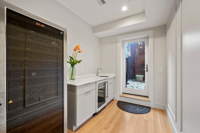 entryway with sink, light hardwood / wood-style flooring, and wine cooler