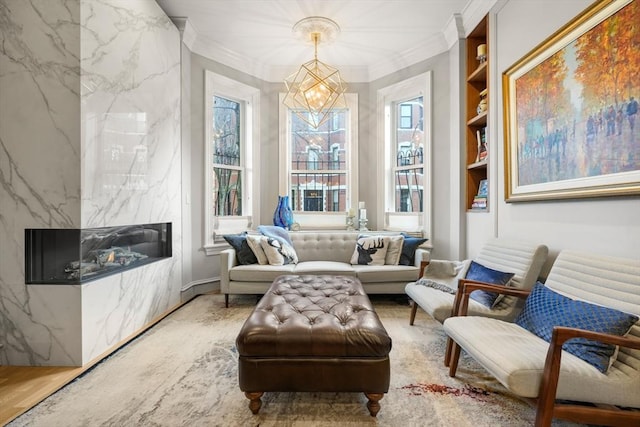 living area with crown molding, a high end fireplace, hardwood / wood-style flooring, built in shelves, and a chandelier