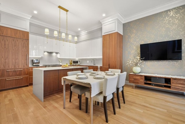 dining room with sink, light hardwood / wood-style flooring, and ornamental molding