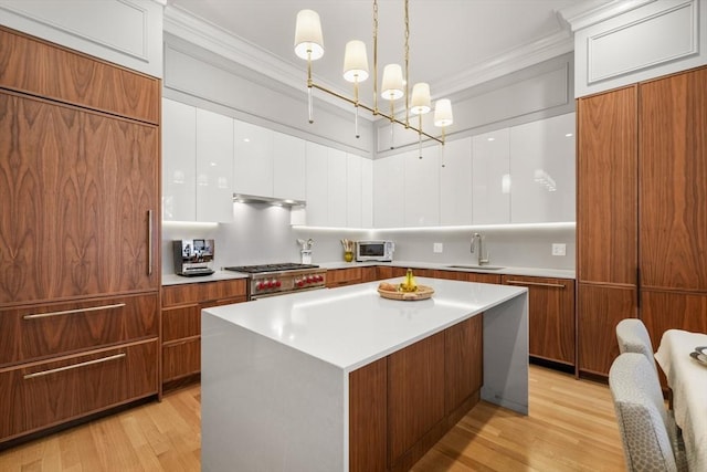 kitchen with a center island, white cabinetry, sink, decorative light fixtures, and paneled refrigerator