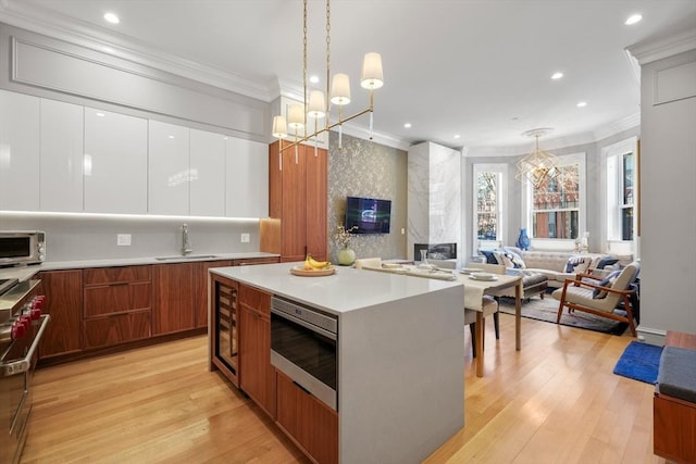 kitchen featuring white cabinetry, hanging light fixtures, sink, a kitchen island, and stainless steel appliances