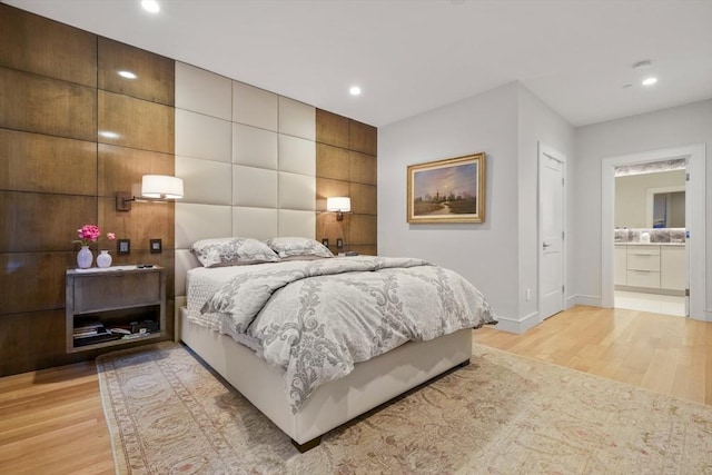 bedroom with light wood-type flooring and ensuite bath