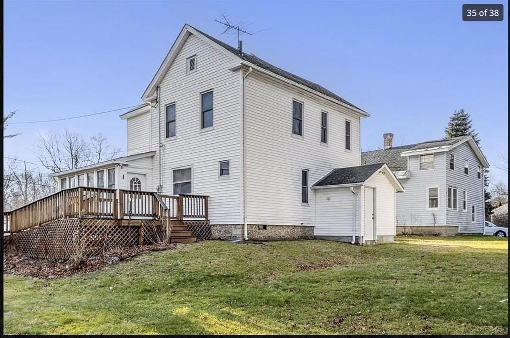 rear view of house with a deck and a lawn