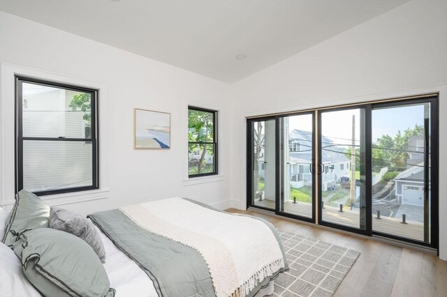 bedroom with light hardwood / wood-style floors, access to outside, and lofted ceiling