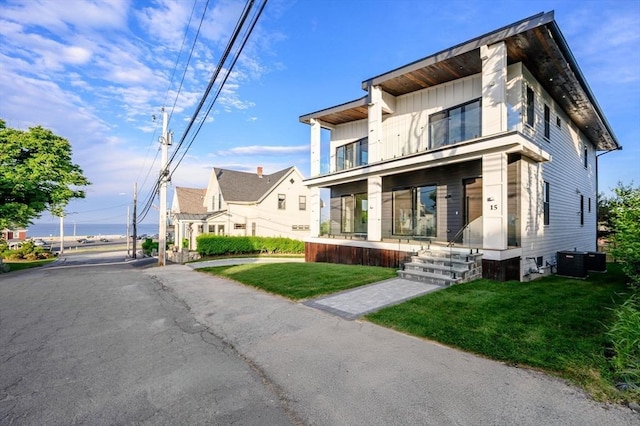 modern home featuring central air condition unit and a front yard