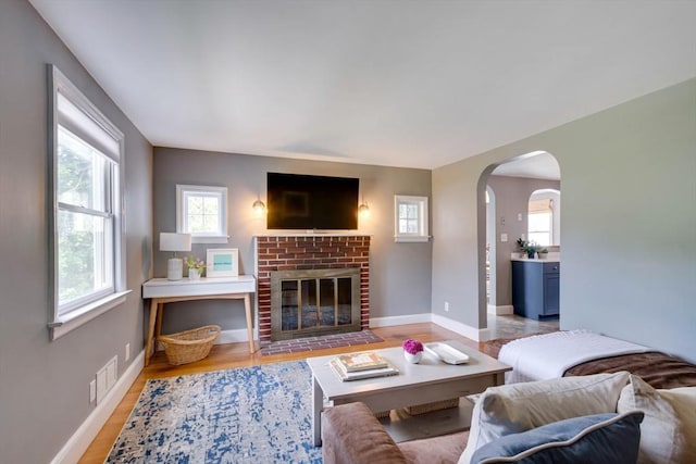 477 Laws Brook Rd, Concord, MA 01742 - living room featuring arched walkways, baseboards, light wood-style floors, and a brick fireplace