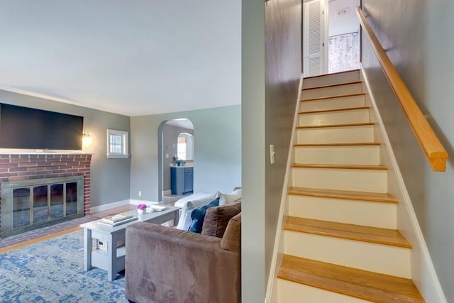 477 Laws Brook Rd, Concord, MA 01742 - staircase featuring arched walkways, a brick fireplace, and baseboards
