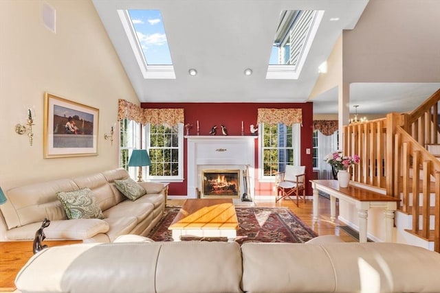 living room with a glass covered fireplace, a healthy amount of sunlight, and a skylight