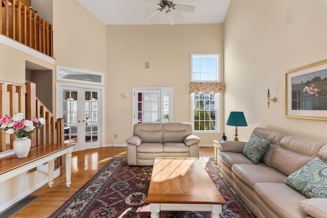 living area with wood finished floors, french doors, a towering ceiling, and ceiling fan