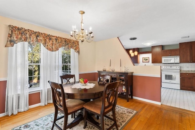 dining space with a chandelier, visible vents, light wood-type flooring, and baseboards