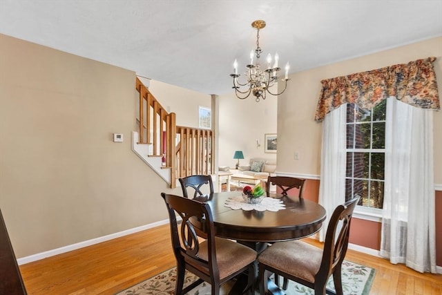 dining room featuring stairway, light wood-style floors, baseboards, and a chandelier