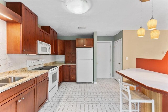 kitchen with tasteful backsplash, light floors, light stone counters, hanging light fixtures, and white appliances