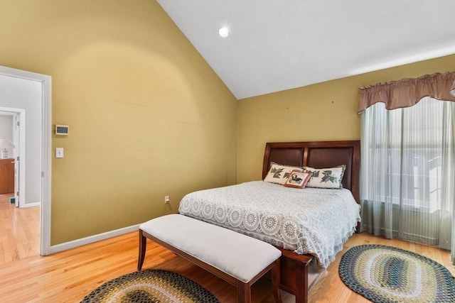 bedroom featuring wood finished floors, baseboards, and high vaulted ceiling