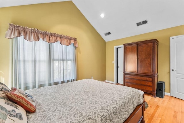 bedroom featuring visible vents, baseboards, light wood-style floors, and high vaulted ceiling