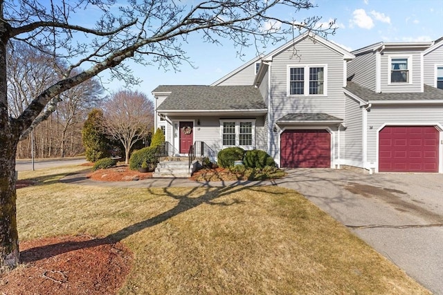 traditional home featuring a garage, a front lawn, driveway, and a shingled roof