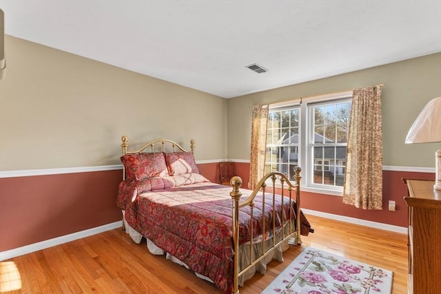 bedroom featuring visible vents, baseboards, and wood finished floors