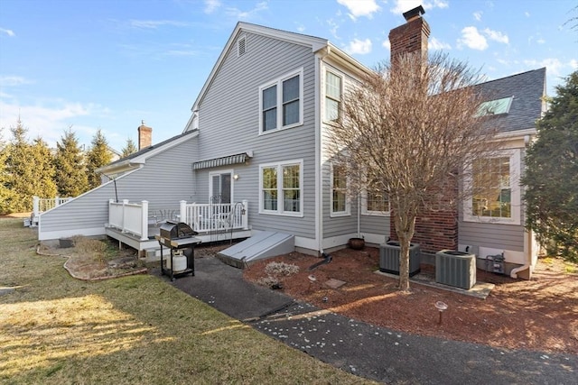 rear view of property featuring a deck, a yard, cooling unit, and a chimney