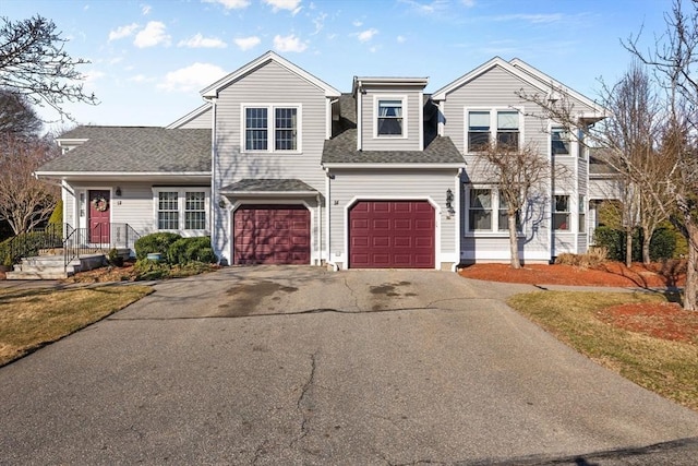 view of front of home with a garage, driveway, and a shingled roof