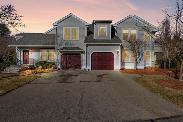 traditional-style home with aphalt driveway, a garage, and a shingled roof